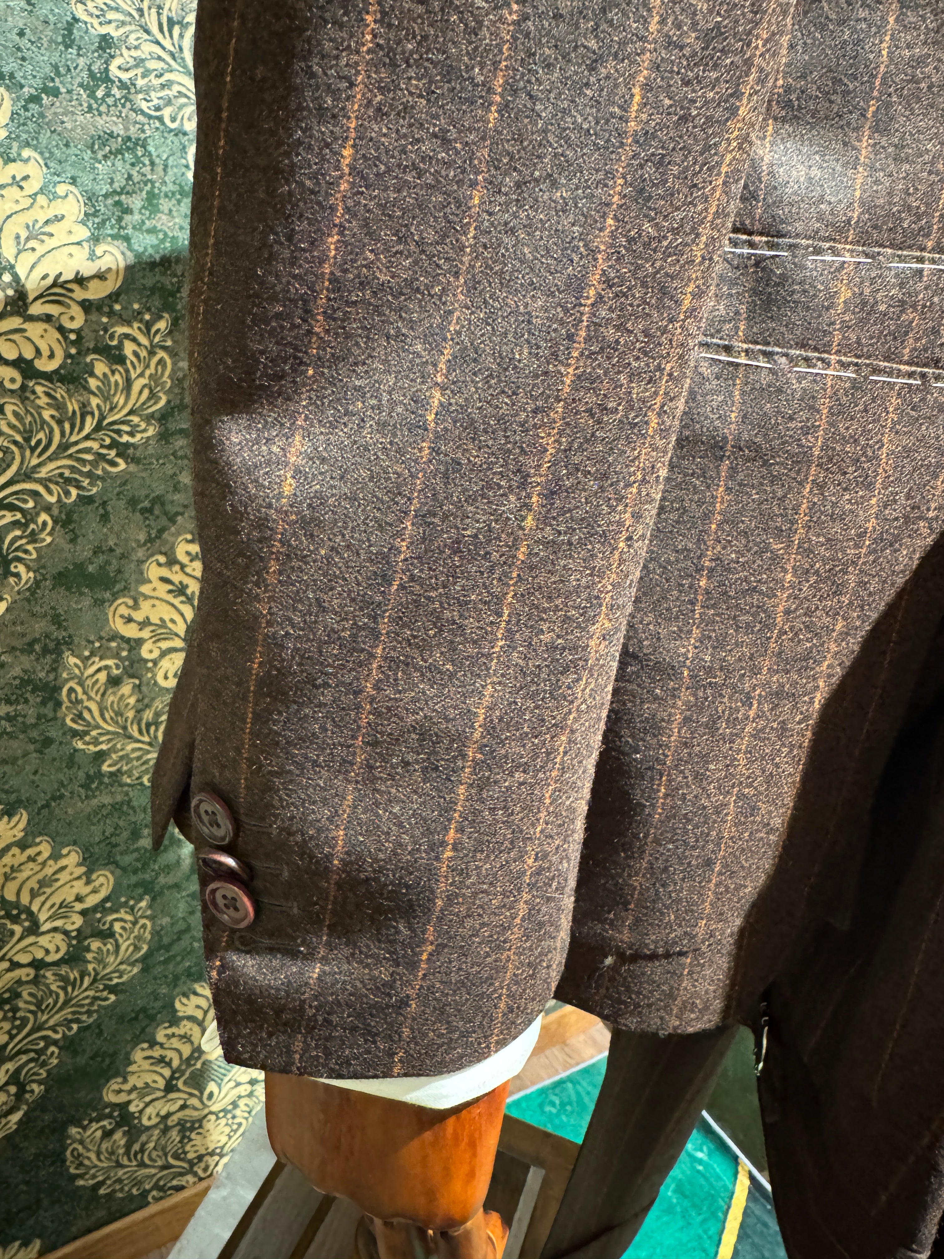 Zweireihiger brauner Nadelstreifenanzug mit orangefarbenen Streifen.