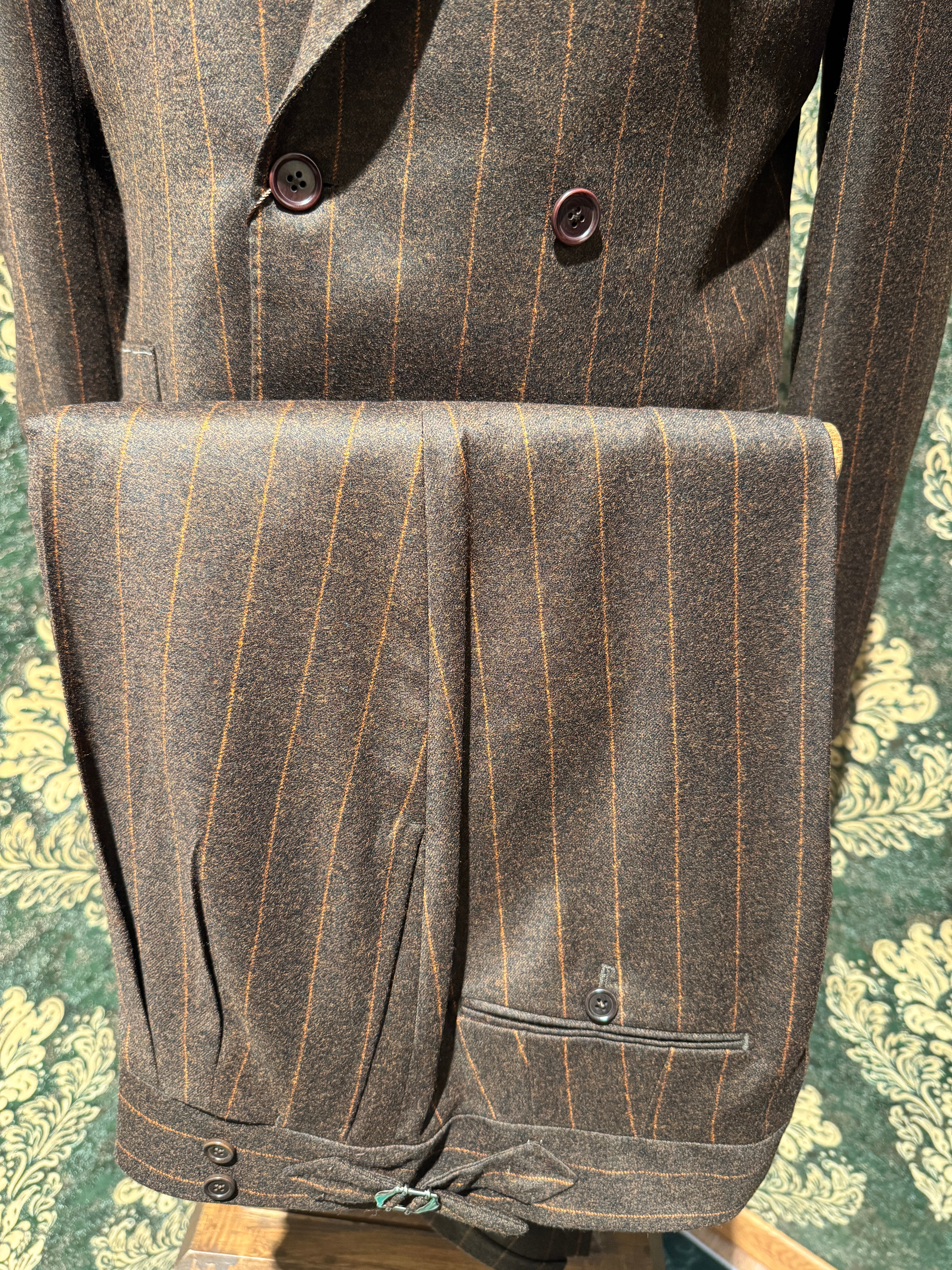 Zweireihiger brauner Nadelstreifenanzug mit orangefarbenen Streifen.